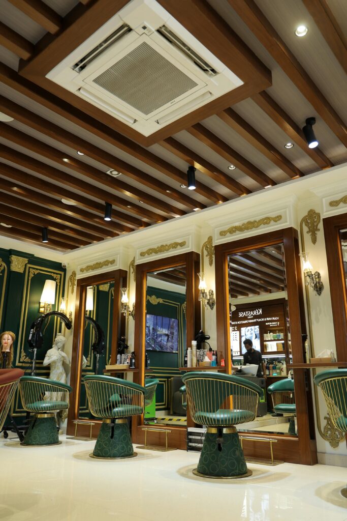 Luxurious hair salon with stylish green and gold decor, mirrored styling stations, and vibrant lighting.